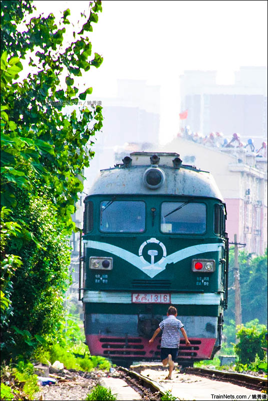 2016年6月24日，夏日的枣庄冶金专用线，单机西瓜返回枣庄东站。一名顽皮的孩童在追逐着前进的机车。（图/姚秀谦）
